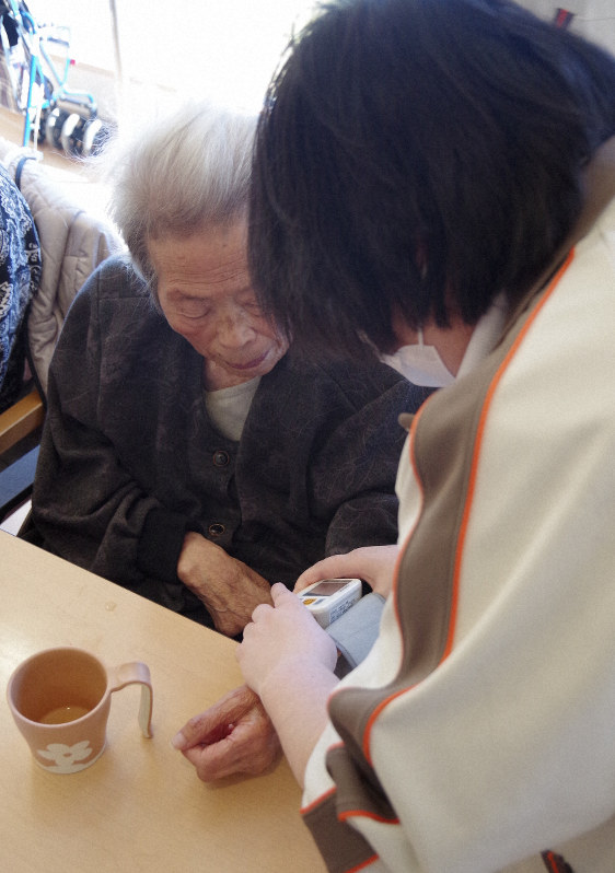 施設利用者(左)の血圧を測る看護師の女性=宮城県気仙沼市の「はまなすの丘」で、新井敦撮影