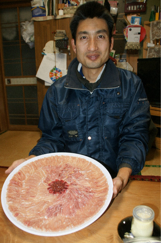 大皿に咲く花のような二ホンキジの刺身を手にする小倉さん