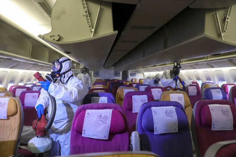 新型肺炎の感染拡大を防ぐため、飛行機内を消毒するタイ国際航空の職員=バンコク郊外のスワンナプーム国際空港で28日、ロイター