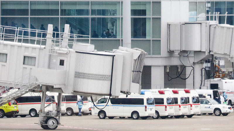 救急車が待機するなか、中国・武漢から到着したチャーター機を降りる人たち(左奥)=羽田空港で2020年1月31日午前11時、吉田航太撮影