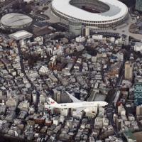 羽田空港の新飛行ルートの実機飛行確認が始まり、都心上空を飛行する航空機。上は国立競技場＝東京都渋谷区で２０２０年２月２日午後４時４９分、本社ヘリから