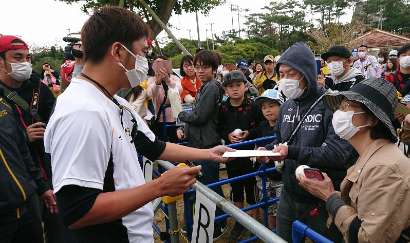 マスクをしてファンサービスする阪神の藤川球児選手(手前左)=沖縄県宜野座村で2020年2月5日、田中将隆撮影