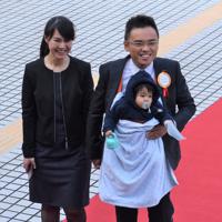 赤ちゃんを胸に抱き、妻と共に赤じゅうたんの上を歩く国民党の洪孟楷氏＝台北市の立法院で2020年2月1日、福岡静哉撮影