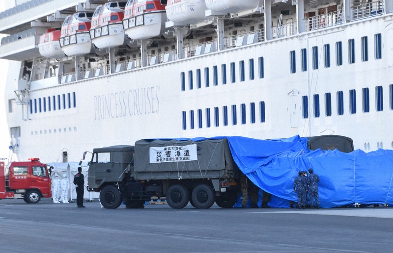 クルーズ船「ダイヤモンド・プリンセス」から続くブルーシートを車両に固定する自衛隊員ら=横浜市鶴見区の大黒ふ頭で2020年2月10日午後3時48分、池田直撮影