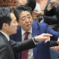 衆院予算委員会で質問を終えた立憲民主党の辻元清美幹事長代行に対する閣僚席からの自身の発言で審議が中断し混乱する中、野党議員（手前）から抗議を受ける棚橋泰文委員長に声をかける安倍晋三首相（奥）＝国会内で２０２０年２月１２日午後２時４９分、川田雅浩撮影