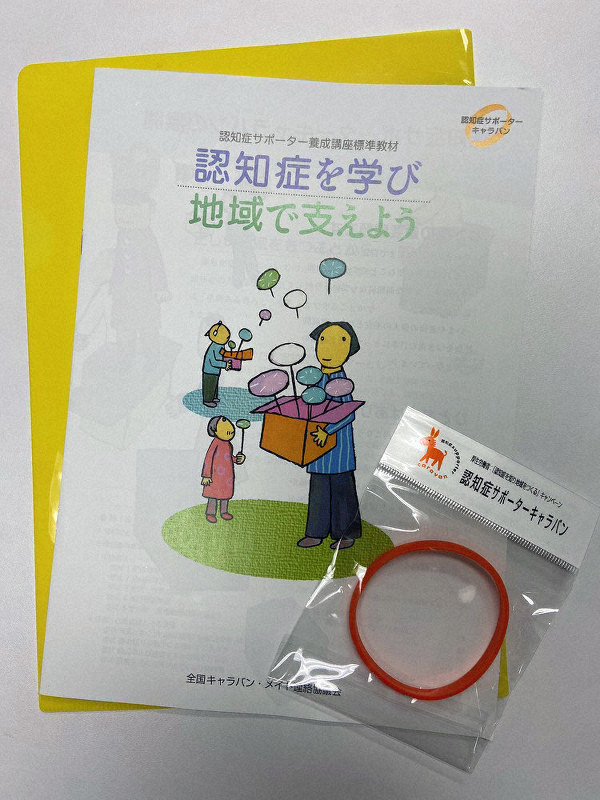 認知症サポーター養成講座の教材と修了者に渡されるオレンジリング=眞鍋さん提供