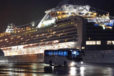 クルーズ船（奥）から下船した米国人を乗せて出発するバス＝横浜市鶴見区で2020年2月17日、竹内紀臣撮影