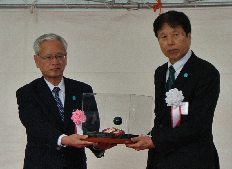 富山ライトレールの粟島康夫社長(右)からコントロールレバーのレプリカを受け取る辻川徹・富山地鉄社長=富山市牛島町の富山駅北仮停留所で、青山郁子撮影