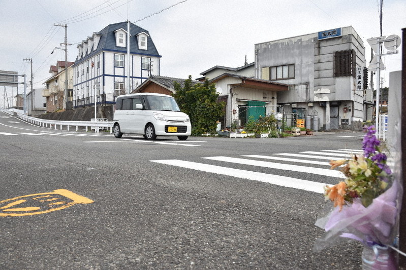 2019年1月に歩行中の高齢女性が車にはねられ、死亡した信号のない横断歩道(手前)。今も花が供えられている=御坊市の県道で、木原真希撮影