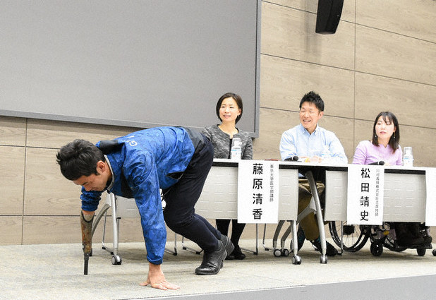右腕に競技用義手をはめ、クラウチングスタートの実演をする多川さん(左)