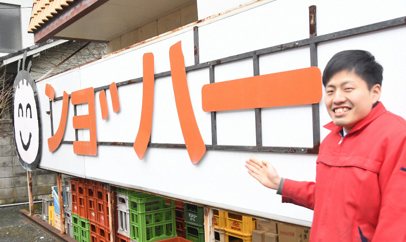 看板を紹介する渡部勝也さん。今は店舗西側の駐車場に展示されている=愛媛県大洲市長浜で2020年2月7日午後2時5分、目野創撮影