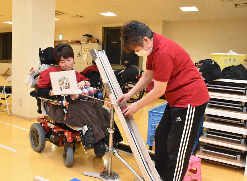 滑り台に似た補助器具「ランプ」を使ってボッチャの練習をする大林さんと補助をする松田さん(右)