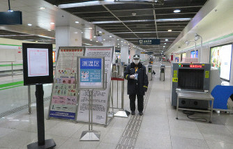 中国・上海の地下鉄の自動改札付近で利用者の検温のため待機する駅関係者=上海市内で2020年2月13日、工藤哲撮影