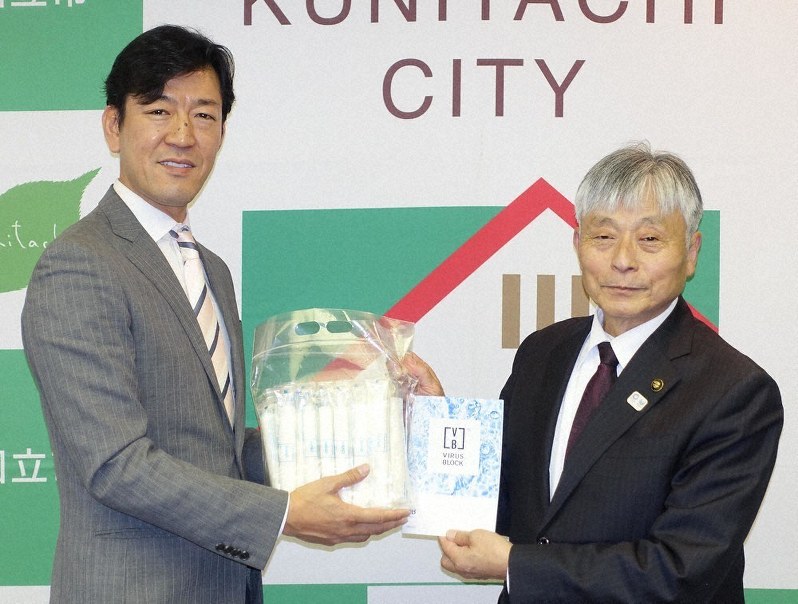 抗菌おしぼりを永見理夫市長(右)に手渡す「FSX」の藤波克之社長=国立市役所で