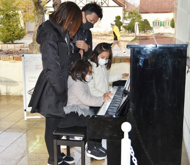 設置されたストリートピアノで演奏を楽しむ親子連れ=日野町西大路の「ブルーメの丘」で、蓮見新也撮影