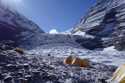 雪煙を上げる大きな雪崩。ベースキャンプから撮影。右の岩壁から雪崩の箇所がキャンプ1に向かうルートだ＝2019年10月4日午前、藤原章生撮影