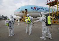 Workers wearing protective gear arrive to disinfect the airplane for New York as a precaution against the new coronavirus at Incheon International Airport in Incheon, South Korea, on March 4, 2020. (Suh Myoung-geon/Yonhap via AP)