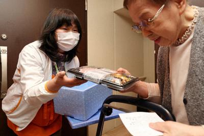 １人暮らしの野口納さん（右）にお弁当を届けるワタミ「まごころスタッフ」の小泉貴世さん＝東京都江戸川区で、宮武祐希撮影