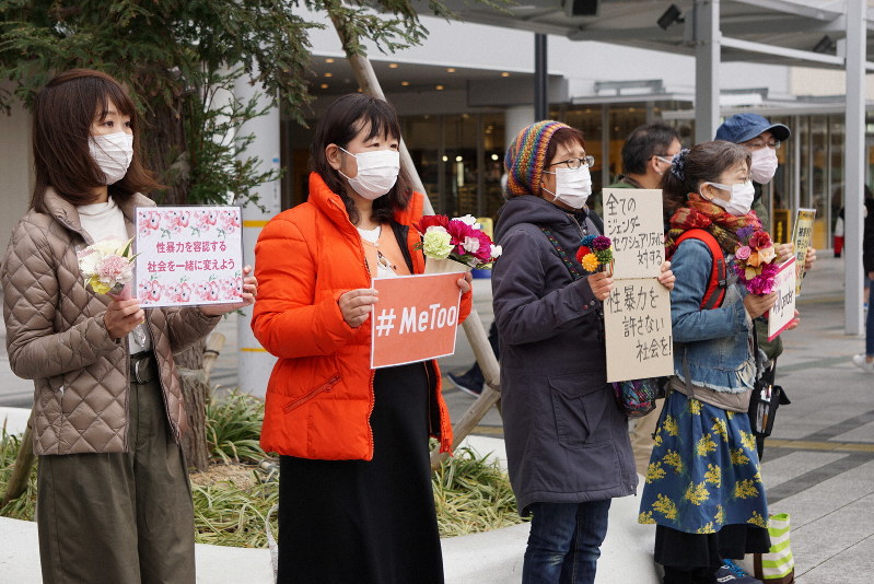 花とメッセージボードを手に、性暴力に抗議するフラワーデモの参加者ら=兵庫県明石市のJR明石駅前で2020年3月8日午後3時2分、反橋希美撮影
