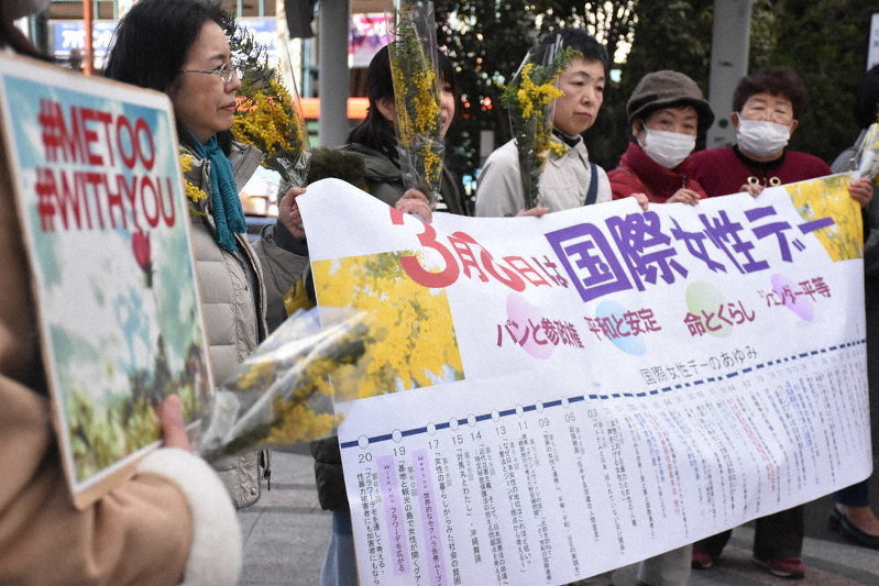 「国際女性デー」の横断幕を掲げて声を上げる女性たち=松山市湊町5の坊っちゃん広場で2020年3月8日、遠藤龍撮影