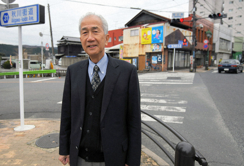 かつて聖火リレーで走った秋川街道と旧青梅街道の分岐点に立つ遠藤良宏さん=東京都青梅市で1月、手塚耕一郎撮影