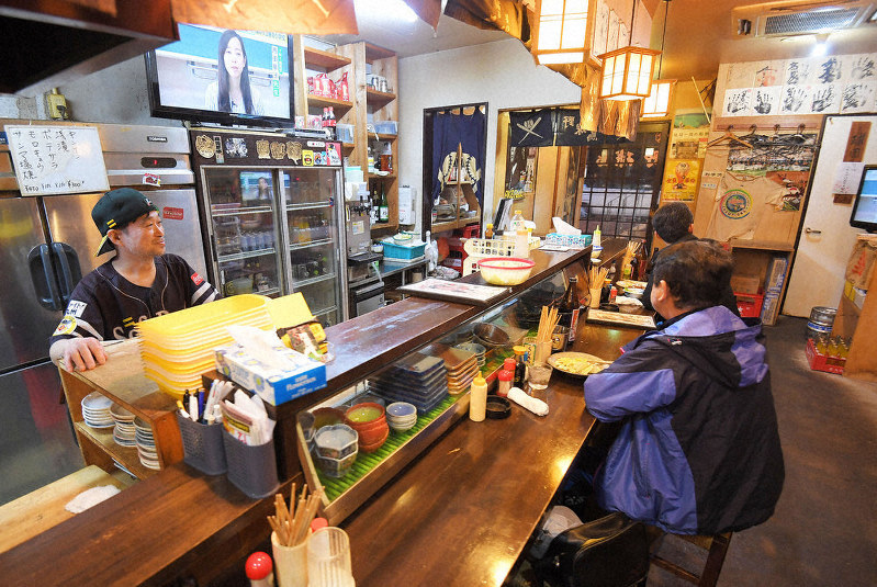 ソフトバンクファンが集まる店でプロ野球の開幕延期について常連客と話す焼き鳥屋の従業員(左)=福岡市中央区で2020年3月9日、津村豊和撮影