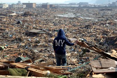 市街地だった場所を見下ろす高台に立ち尽くす女性。恋人と連絡が取れず手がかりを探そうと思ったが「どこに何があったかもわからない」と涙をこらえ切れなかった＝岩手県陸前高田市で２０１１年３月１３日午後２時４分、小川昌宏撮影