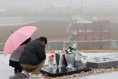 雨の降る中、震災復興祈念公園の「祈りの丘」で手を合わせる人たち。丘の上からは町職員らが犠牲になった防災対策庁舎や、今なお造成工事が続く町の景色が一望できた＝宮城県南三陸町で２０２０年３月１０日午前１０時２８分、喜屋武真之介撮影