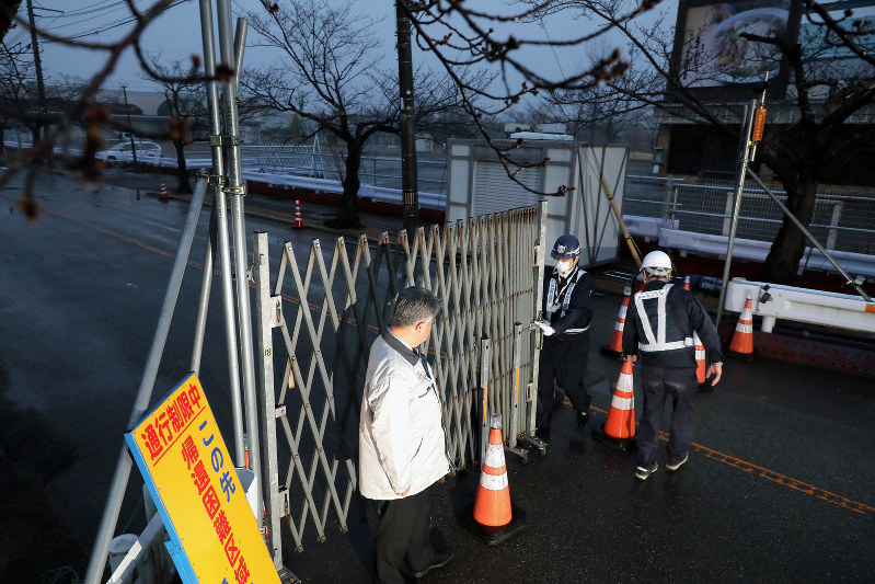 避難指示が一部解除され、桜並木の道路に設けられていたゲートを開ける作業員=福島県富岡町で2020年3月10日午前6時、和田大典撮影