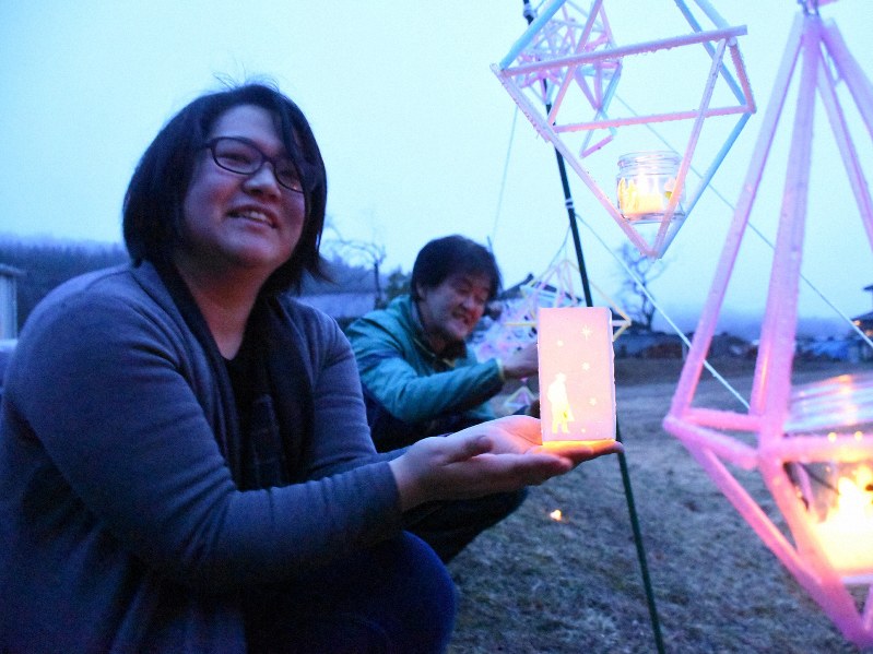 仲間と灯籠(とうろう)に明かりをともす覚張あゆみさん(左)=岩手県陸前高田市竹駒町で2020年3月9日午後5時49分、三瓶杜萌撮影