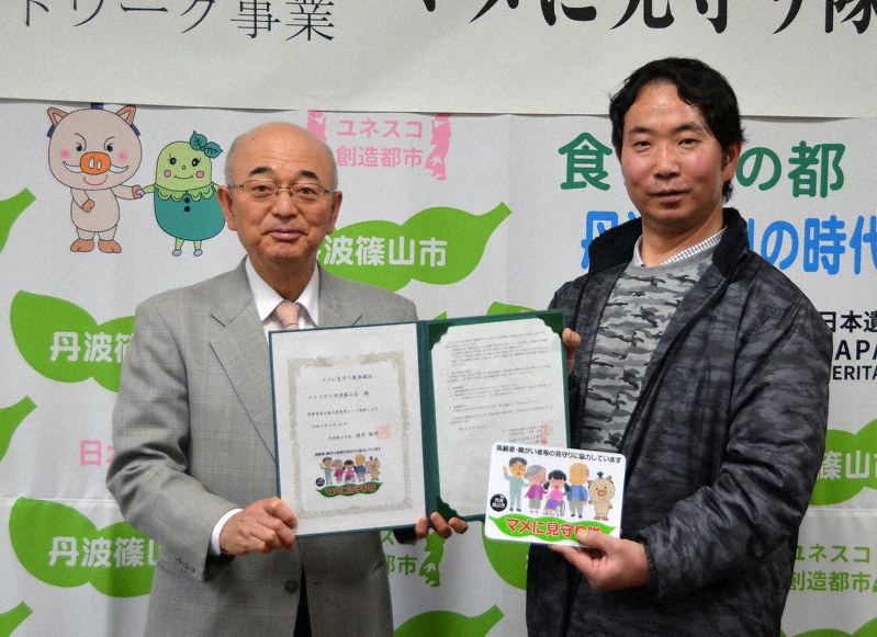 酒井隆明市長(左)から見守り隊の登録証とステッカーを受け取る杉本弘樹オーナー=丹波篠山市役所で、丸井康充撮影