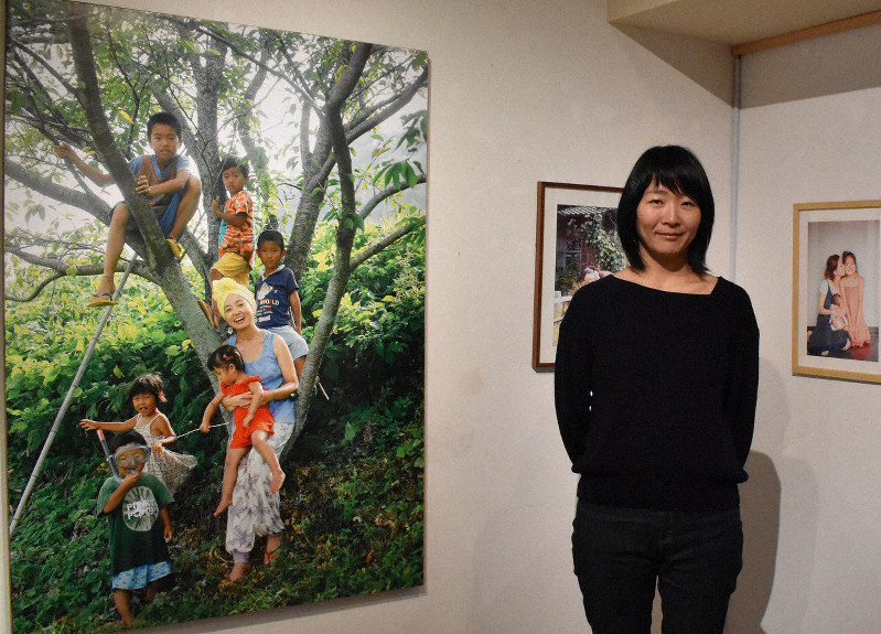 フォトグラファーの亀山さんと、母子の写真が並ぶ会場