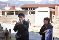 Former junior high school teacher Toshiro Sato, left, livestreams a class in front of the remains of Okawa Elementary School in the city of Ishinomaki, Miyagi Prefecture, on March 11, 2020. Sato, who lost one of his daughters to the tsunami ensuing the 2011 Great East Japan Earthquake, hoped his lecture would provide an opportunity for people to think about disaster prevention. (Mainichi/Daisuke Wada)