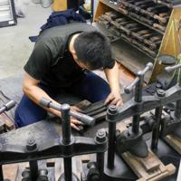 墨を練って型に入れる職人。手前の道具でプレスして成形する＝奈良市で、大森顕浩撮影