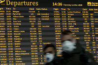 People walk by a departures monitor at the Rome Leonardo da Vinci International Airport, on March 12, 2020. (AP Photo/Andrew Medichini)