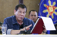 In this handout photo provided by the Malacanang Presidential Photographers Division, Philippine President Rodrigo Duterte gestures as he delivers his speech at the Malacanang Presidential Palace in Manila, Philippines, on March 12, 2020. (Richard Madelo/ Malacanang Presidential Photographers Division via AP)