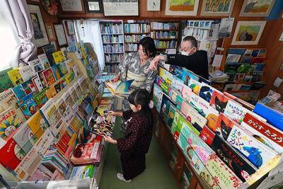 訪れた客が手に取る絵本の良さを語る青田正徳さん（右）＝札幌市手稲区で２０２０年３月１３日、貝塚太一撮影