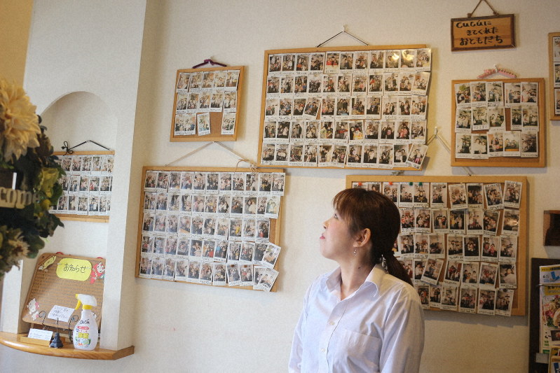 「家に閉じこもっていては親子ともにストレスがたまる。お店に来て」。開店以来のお客の写真を見ながら呼びかける岡田さん=2020年3月12日、小倉北区吉野町で伊藤和人撮影
