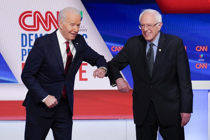 米大統領選に向けた民主党の候補者テレビ討論会で、新型コロナウイルス感染予防のため握手の代わりに肘をぶつけてあいさつするバイデン前副大統領(左)とサンダース上院議員=ワシントンで2020年3月15日、AP