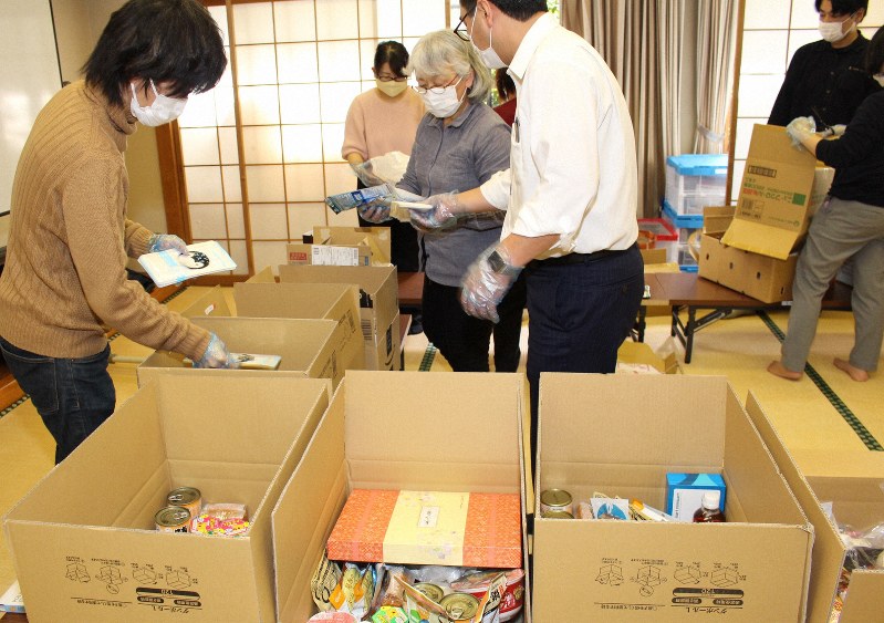 ひとり親家庭に配る食料などを箱に詰め込むNPO法人「太陽の家」のスタッフら=桑名市で20年3月9日、松本宣良撮影