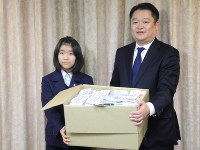 Hime Takimoto, left, presents a box of her handmade masks to Yamanashi Gov. Kotaro Nagasaki at the prefectural government headquarters on March 17, 2020. (Mainichi/Kenji Noro)