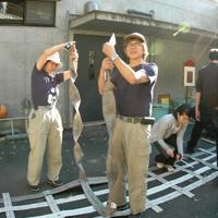 使用済みの消防用ホースでオランウータンが使うつり橋の作り方を説明する黒鳥英俊さん(中央)=日野市の多摩動物公園で2008年