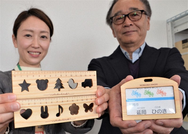 延岡産ヒノキ製の名札ケースや定規を手にする家村理事長(右)と吉川さん
