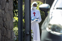 A nun wearing a mask and gloves stands at the Istituto Figlie di San Camillo (Institute of Daughters of St. Camillo) in Grottaferrata, near Rome, on March 20, 2020. (Roberto Monaldo/LaPresse via AP)