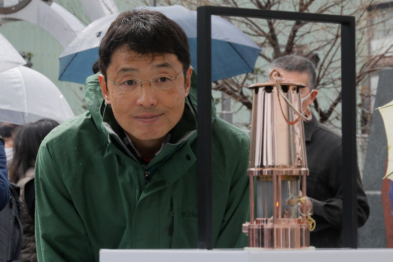 釜石駅前で「復興の火」として展示される東京オリンピックの聖火のランタンを見つめる三上雅弘さん=岩手県釜石市で2020年3月22日午後0時2分、和田大典撮影