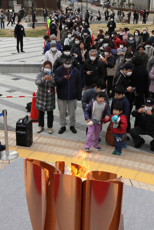 「復興の火」として聖火皿にともされた東京オリンピックの聖火を見る人たち=岩手県大船渡市で2020年3月23日午前10時24分、和田大典撮影