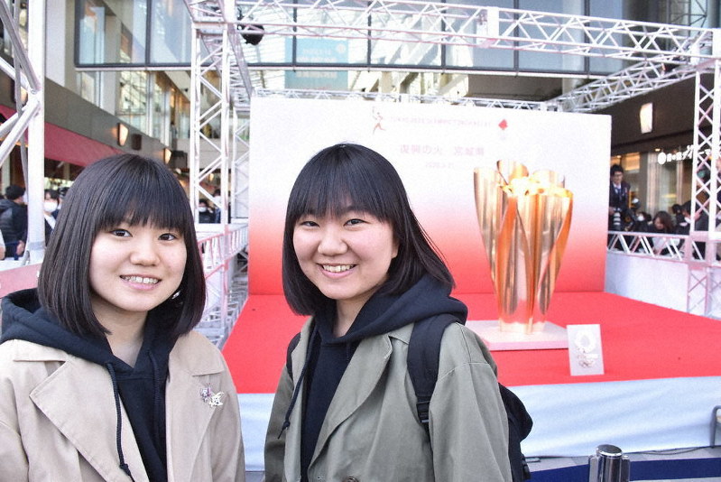 「復興の火」を背に記念撮影する井崎英里さん(左)と英乃さん=JR仙台駅東口で