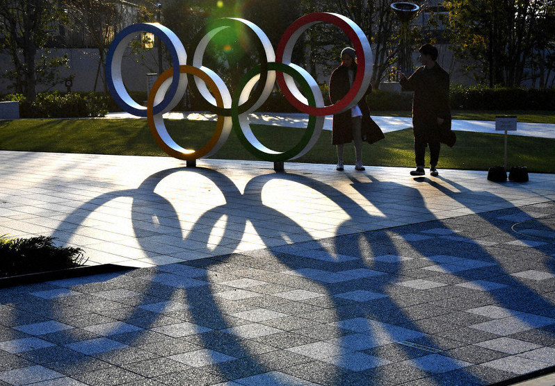 夕日に照らされ影が伸びる日本オリンピック委員会前の五輪マークのモニュメント=東京都新宿区で2020年3月23日午後4時56分、大西岳彦撮影