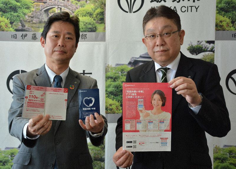 「電話お願い手帳」を贈ったNTT西日本の(左から)和田・北九州支店ビジネス営業部長と小野・筑豊営業支店長