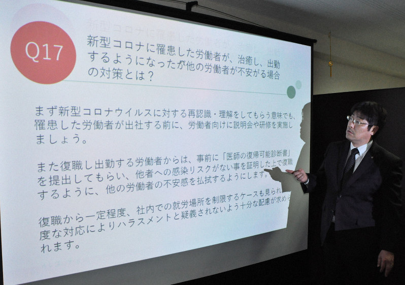 作成したガイドブックをスクリーンに映し、解説する社労士の村里正司さん=福岡市博多区で2020年3月25日午後4時56分、平塚雄太撮影